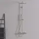 Duschsystem an einer Wand mit Regenbrause und Handbrause. Die Armatur und Halterungen sind in einem neutralen Ton gehalten. Ideal Standard ist als Marke erkennbar.